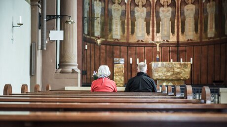 Ein älteres Paar sitzt in den Kirchenbänken der Abteikirche der Benediktinerinnenabtei Sankt Hildegard in Rüdesheim. / © Julia Steinbrecht (KNA)