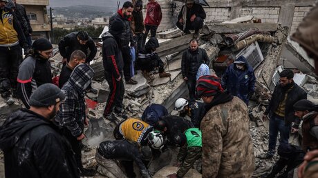 Zivilisten und Mitglieder der Weißhelme arbeiten in Idlib in Syrien an der Rettung von verschütteten Menschen / © Anas Alkharboutli (dpa)
