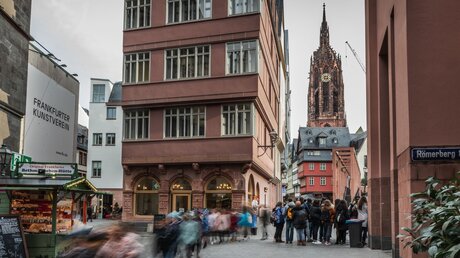 ARCHIV - Menschen gehen an einer beleuchteten Bude vorbei in einer Straße am Frankfurter Kunstverein vor dem Dom Sankt Bartholomäus am 29. November 2019 in Frankfurt am Main. Foto: /KNA / © Bert Bostelmann (KNA)