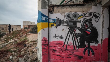 Ein Wandgemälde der Solidarität mit dem ukrainischen Volk ist auf den Überresten eines zerstörten Gebäudes in Binnish, Syrien, zu sehen / © Anas Alkharboutli (dpa)