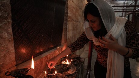 Irak, Lalish: Eine Frau entzündet ein Feuer im Shekadi-Schrein während der Feierlichkeiten des Sommer-Arbaeen-Eids / © Ismael Adnan (dpa)