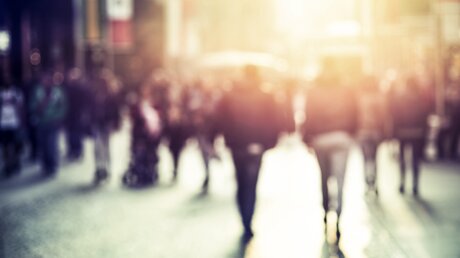 unscharf und abstrakt abgebildete Menschen, die auf einer Straße gehen (Symbolbild: Straßenexerzitien) / © Alextype (shutterstock)