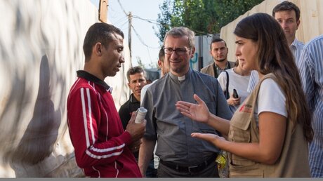Erzbischof Stefan Heße, Flüchtlingsbeauftragter der Deutschen Bischofskonferenz (m.), spricht beim Besuch in einem inoffiziellen Flüchtlingscamp in der libanesischen Stadt Jdita mit einem syrischen Flüchtling (l.). Eine Caritas-Mitarbeiterin übersetzt. (KNA)
