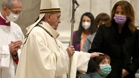 Papst Franziskus streicht über den Kopf eines Jungen, bevor er die Christmette feiert / © Vincenzo Pinto (dpa)