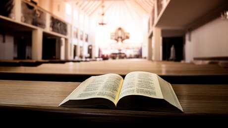 Aufgeschlagene Bibel in einer Kirchenbank / © mojekadry (shutterstock)