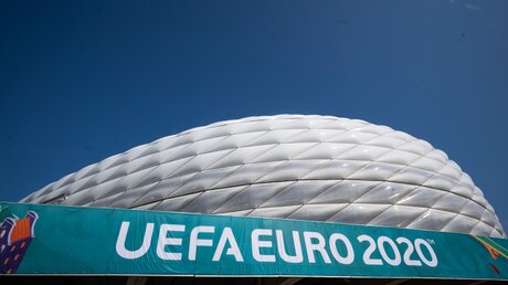 Ein Banner mit der Aufschrift „UEFA Euro 2020“ hängt vor der Allianz Arena in München. / © Peter Kneffel (dpa)