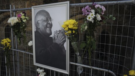 Blumen und ein Foto des anglikanischen Erzbischofs Desmond Tutu hängen an einem Gerüst in der St. George's Kathedrale in Kapstadt / © Uncredited/AP (dpa)