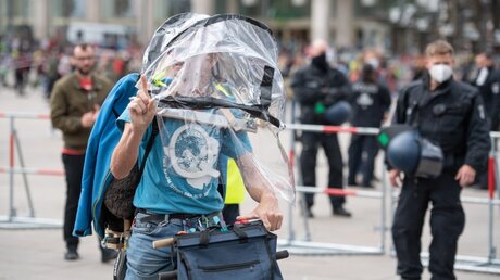 Demonstrant mit einer Schutzkonstruktion und einem Q für "QAnon", Zeichen einer Verschwörungstheorie / © Christophe Gateau (dpa)