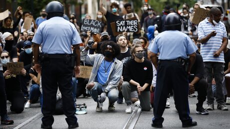 Demonstranten knien bei einem Protest als Zeichen der Solidarität nieder / © Matt Rourke (dpa)