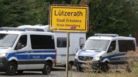 Demonstration am Garzweiler Tagebau: Einsatzfahrzeuge der Polizei stehen hinter dem Ortseingangsschild von Lützerath / © David Young (dpa)