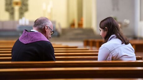 Ein katholischer Pfarrer führt mit einer jungen Frau ein Beichtgespräch in einer Kirchenbank / © Harald Oppitz (KNA)