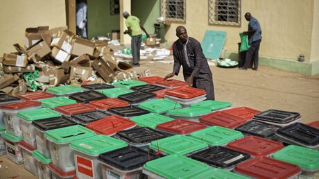 Ein Wahlhelfer trägt und stapelt Wahlurnen in Nigeria / © Ben Curtis (dpa)