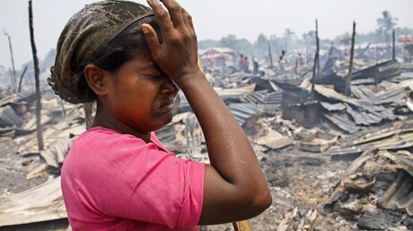 Eine Frau der Rohingya weint in der Nähe nach einem Brandunfall in einem Lager für Binnenvertriebene / © Nyunt Win (dpa)