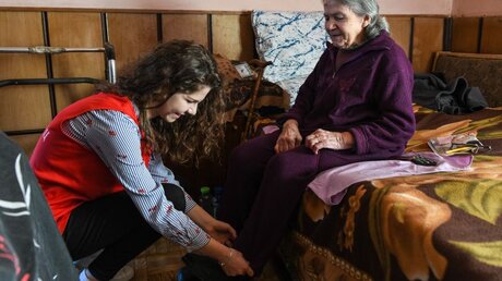 Eine Jugendliche besucht eine alte Frau zu Hause / © Harald Oppitz (KNA)