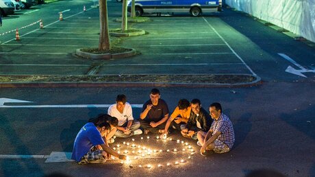 Flüchtlinge am 24.08.15 vor dem ehemaligen Praktiker-Baumarkt in Heidenau vor einem Peace-Zeichen aus Teelichtern (dpa)