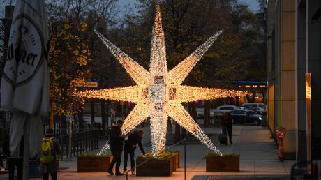 Fußgänger stehen vor einem leuchtenden Stern / © Harald Oppitz (KNA)
