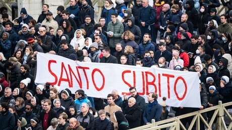 Teilnehmer halten ein großes Banner mit der Aufschrift in roten Lettern Santo Subito (dt. rasche Selig- und Heiligsprechung) beim Requiem für Benedikt XVI. / © Cristian Gennari/Romano Siciliani (KNA)