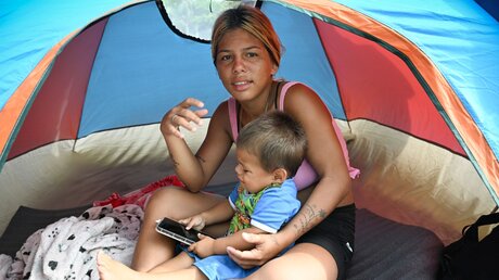 Eine venezolanische Migrantin mit ihrem Kind wartet auf eine Weiterreise durch den Darién nach Panama, am 1. Oktober 2023 in Necocli, Kolumbien / © Tobias Käufer (KNA)