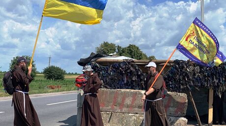 Ordensmänner mit Ukraineflaggen an einer Straßensperre (KiN)