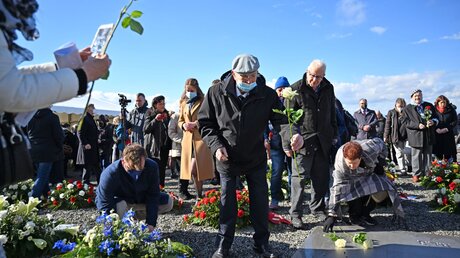Teilnehmer legen auf dem Appellplatz in der Gedenkstätte Buchenwald bei Weimar bei einer Gedenkfeier zur Befreiung des einstigen NS-Konzentrationslagers vor 77 Jahren Blumen nieder. / © Martin Schutt (dpa)
