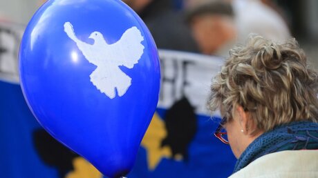 Ein blauer Luftballon mit dem Symbol einer weißen Friedenstaube wird während einer Kundgebung zum Jahrestag des Ausbruches des Zweiten Weltkrieges getragen / © Jens Wolf/dpa-Zentralbild (dpa)