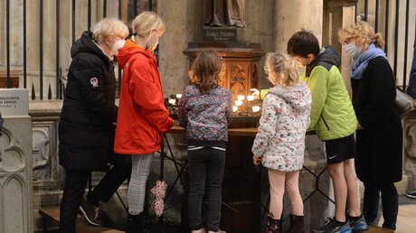Dombesucher zünden ein Licht vor der Antonius-Statue an und bringen ein Kerzenopfer dar. / © Beatrice Tomasetti (DR)