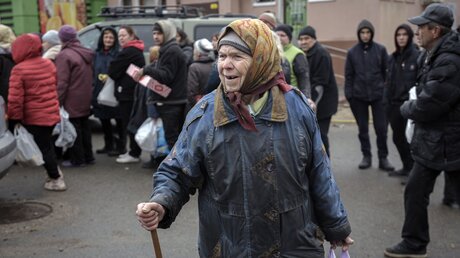 Eine Frau hält eine Tüte mit Lebensmitteln in der Hand, nachdem ein Konvoi von Militär- und Hilfsfahrzeugen in dem ehemals russisch besetzten Kiewer Vorort Butscha eingetroffen ist.  / © Vadim Ghirda/AP (dpa)