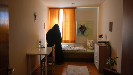 Eine Ordensfrau richtet die Decke in einem Zimmer für Gäste im Benediktinerinnenkloster Sankt Katharina von Siena, am 8. September 2023 in Düsseldorf / © Julia Steinbrecht (KNA)