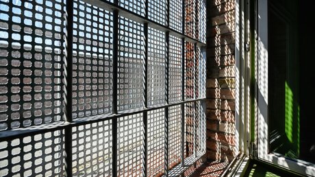 Licht fällt durch ein vergittertes Fenster in der Justizvollzugsanstalt (JVA) Herford / © Julia Steinbrecht (KNA)