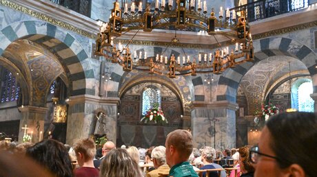 Gottesdienstteilnehmer im voll besetzten Aachener Dom bei der Erhebungsfeier am 9. Juni 2023 in Aachen. Ein Mann trägt das Halstuch mit dem Logo der Heiligtumsfahrt. / © Harald Oppitz (KNA)