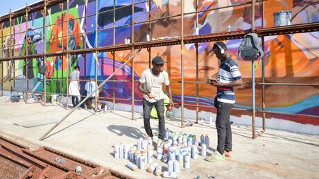 Künstler arbeiten an einem Graffito an der Hafenmauer von Cotonou, anlässlich des Graffiti-Festivals Effet Graff, im Mai 2022 in Cotonou (Benin) / © Katrin Gänsler (KNA)