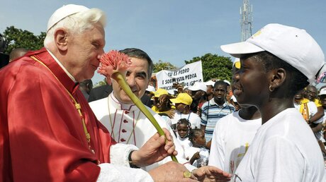Papst Benedikt XVI. wird am 21. März 2009 in den Straßen von Luanda von einem Mädchen mit Blumen beschenkt (KNA)