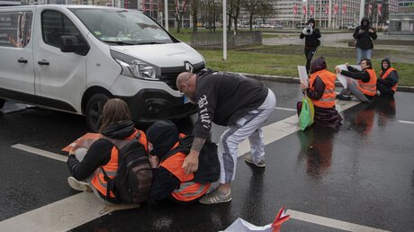 Ein Autofahrer versucht in Berlin, ein Mitglied der Gruppe Letzte Generation von der Straße zu zerren. / © Paul Zinken (dpa)