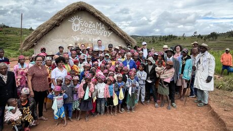 Eine Delegation des Bischöflichen Hilfswerks Misereor steht mit Dorfbewohnern und Kindern am 16. Februar 2023 vor einer neu erbauten Schule bei deren Einweihung in Ambalamanakana (Madagaskar) / © Alexander Brüggemann (KNA)
