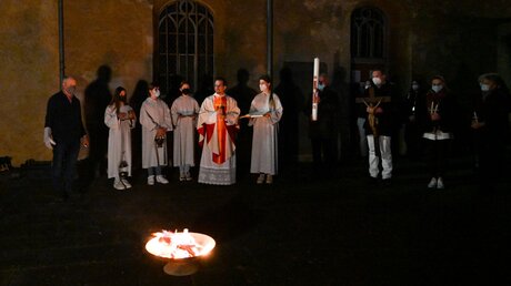 Priester und Ministranten stehen zu Beginn der Osternacht um ein Osterfeuer auf dem Calvarienberg in Ahrweiler / © Harald Oppitz (KNA)