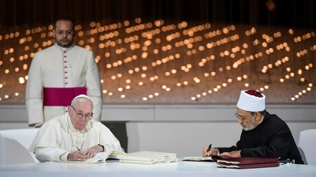 Papst Franziskus und Großscheich Ahmad al-Tayyeb (Ahmed al-Tayyib)unterzeichnen Dokumente einer gemeinsamen Erklärung während eines Treffens in Abu Dhabi. / © Romano Siciliani/ Vatican Media (KNA)