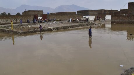 Jungen waten durch ein überschwemmtes Gebiet am Rande von Quetta. Bei schweren Regenfällen im Südwesten Pakistans sind mindestens neun Menschen ums Leben gekommen. / © Arshad Butt/AP (dpa)