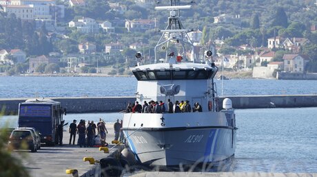 Migranten gehen nach einer Rettungsaktion im Hafen von Mytilene von einem Schiff der griechischen Küstenwache an Land / © Panagiotis Balaskas (dpa)