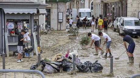 Menschen entfernen Schlamm von einer Straße in Senigallia, Mittelitalien. Durch heftige Regenfälle ausgelöste Sturzfluten haben Städte im hügeligen Mittelitalien überschwemmt. / © Guido Calamosca/LaPresse via AP (dpa)