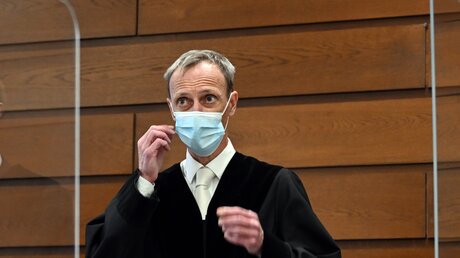 Der vorsitzende Richter Christoph Kaufmann nimmt im Gerichtssaal seine Maske ab / © Federico Gambarini (dpa)