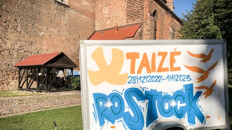 Ein Anhänger vor der Kirche Sankt Petri in Rostock wirbt am 31. August 2022 für das bevorstehende europäische Taize-Jugendtreffen in Rostock. / © Nicola Trenz (KNA)