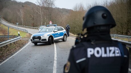 Polizeibeamte stehen an einer Absperrung an der Kreisstraße 22 rund einen Kilometer von dem Tatort, an dem zwei Polizeibeamte durch Schüsse getötet wurden / © Sebastian Gollnow (dpa)