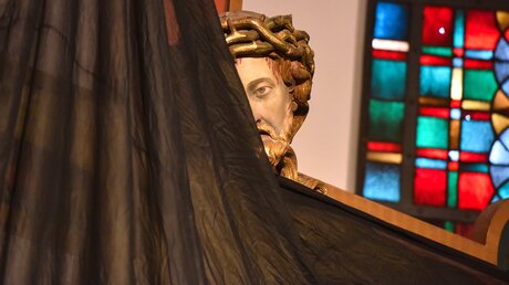 Das Kreuz in der Apsis einer Kirche in Bonn wird mit einem schwarzen Tuch verhüllt. Es ist nur noch der Kopf von Jesus mit der Dornenkrone zu sehen. / © Harald Oppitz (KNA)