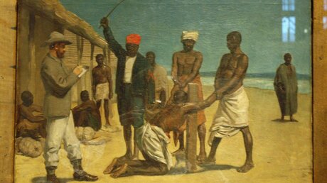 Eine Abbildung von Vorarbeitern, die einen Schwarzen Sklaven auspeitschen. / © Alexander Brüggemann (KNA)