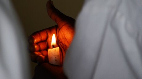 Mann mit einer Kerze in einer südafrikanischen Kirche / © Adriana Mahdalova (shutterstock)