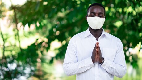 Afrikaner mit Atemschutzmaske im Gebet / © arrowsmith2 (shutterstock)