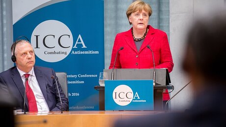 Bundeskanzlerin Angela Merkel (CDU) spricht am 14.03.2016 bei der ICCA Antisemitismus Konferenz in Berlin neben dem Vorsitzenden der ICCA, John Mann. / © Michael Kappeler (dpa)