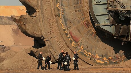  Jüchen: Polizeibeamte stehen in der Braunkohlengrube Garzweiler vor einem Schaufelradbagge / © David Young (dpa)