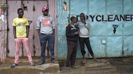 Junge Kenianer stehen in Nairobi vor geschlossenen Läden im Kibera Slum. / © Jerome Delay (dpa)
