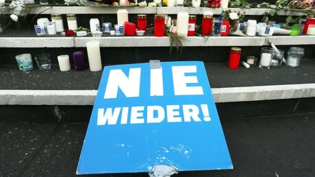 Kerzen, Blumen und ein Plakat mit der Aufschrift "Nie wieder" vor der Düsseldorfer Synagoge / © David Young (dpa)
